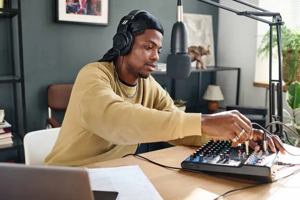 Photo of African American guy plugging cord into soundboard before adjusting it