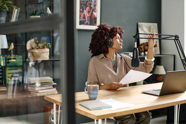 istock Young distracted female radio presenter with paper adjusting microphone 1790922575