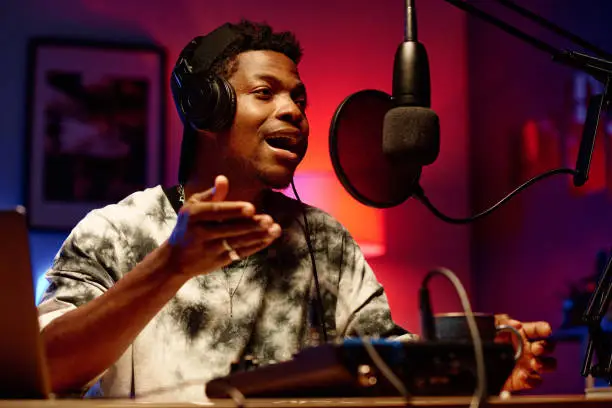 Photo of Young male radio presenter in headphones talking in microphone