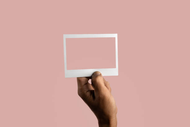 istock black male hand holding photo frame on isolated on light pink background 1790961673