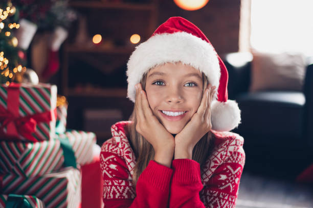 istock Photo of pretty dreamy little lady dressed red print pullover hands arms cheeks cheekbones enjoying x-mas christmas spirit indoors home room 1790987510
