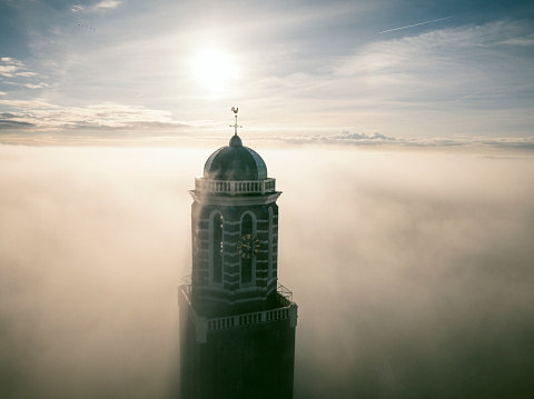 The Peperbus tower of the The Roman Catholic Onze Lieve Vrouwe ten Hemelopneming-basilica church in Zwolle rising up above the fog. The church tower, called Peperbus (pepperpot), is one of the tallest and most famous church towers in the Netherlands.