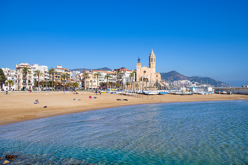 Beach and seafront of Sitges, with the imposing Church of St. Bartholomew and St. Thecla, dating back to the 17th century