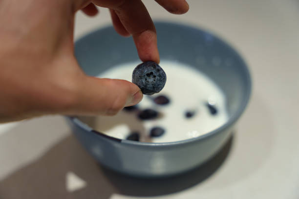 istock Berry Bliss: Hands Holding Fresh Blueberries Over a Bowl of Kumis 1791019580