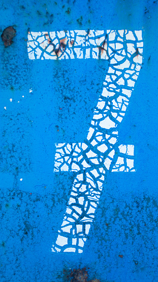 Cracked paint number seven on blue metal surface