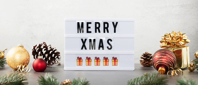 Lightbox with text Merry xmas and christmas decor on the table against white background. Front view banner