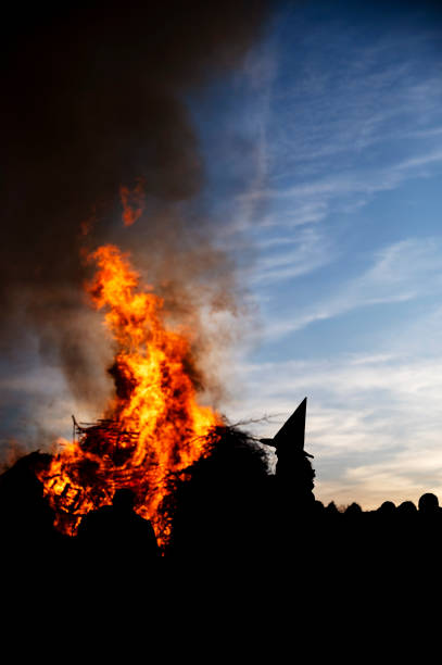 A girl dressed as a witch sits on her father's shoulder in front of the big traditional bonfire on Walpurgis Night.