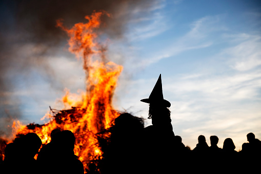A girl dressed as a witch sits on her father's shoulder in front of the big traditional bonfire on Walpurgis Night.
