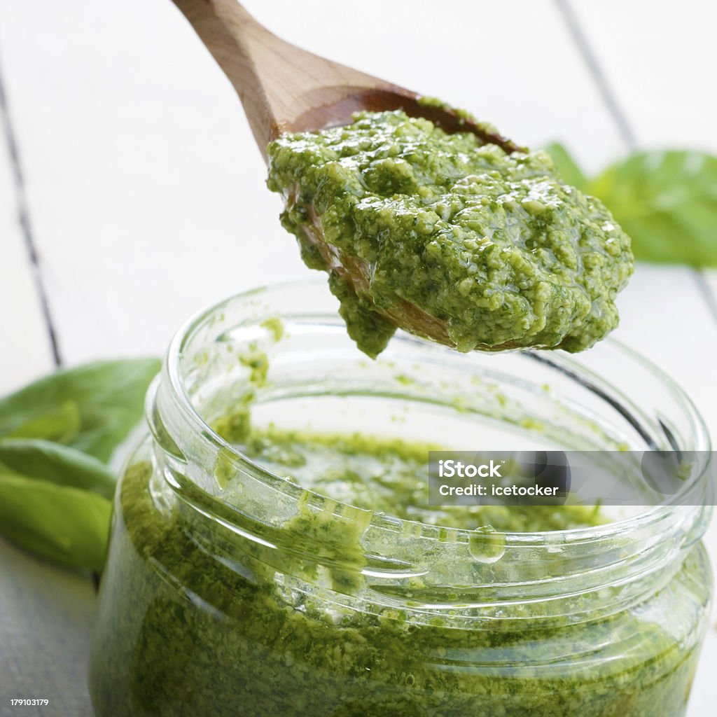 Pesto sauce and spoon Glass jar of pesto sauce with wooden spoon Basil Stock Photo