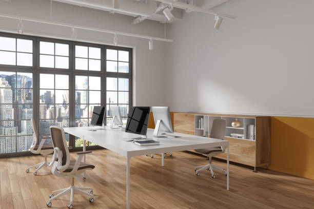 istock Stylish coworking interior with pc monitors and drawer, window. Mockup wall 1791036423