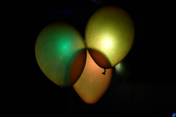 Yellow dumbbell with a bow and balloon in background. Exercise equipment as a birthday party gift idea. Gym workout and sport training composition, healthy fitness lifestyle concept with copy space.