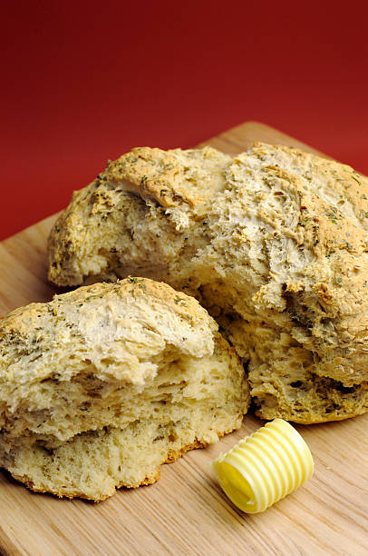 Australian traditional beer batter damper bread - closeup Australian traditional beer batter damper bread with buuter curls on bread board against a red ochre background. Vertical close up. beer damper stock pictures, royalty-free photos & images