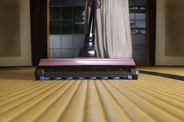 Black and white battery-powered vacuum cleaner, vacuuming the dirty carpet in the living room, cleaning the apartment, preparing for the holidays, Christmas cleaning