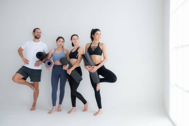 eine gruppe von sportlerinnen und sportlern stand und plauderte freundschaftlich im studio, bevor es mit der yogastunde begann. - amicably stock-fotos und bilder