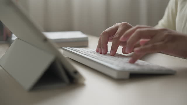 Hands typing on a external bluetooth computer keyboard working on a digital tablet