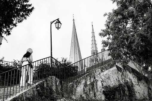 Woman climbing steps with view of the spires of Chartres Cathedral, in the town of Chartres, south west of Paris, France.