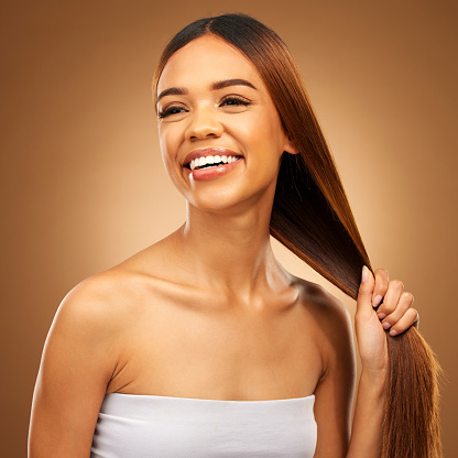 Haircare, smile and woman with strong straight hair in hand and studio space with texture and salon shine. Beauty model, healthy hairstyle and natural keratin product promotion on brown background.