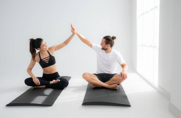istock Young couple practicing yoga in a white room of studio. 1791101713