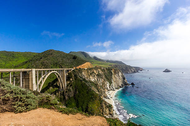Bixby Bridge on the California Coastline "The Bixby Bridge on the Big Sur Coast with fog and the crashing waves of the Pacific Ocean.South of Carmel-by-the-Sea , California" Bixby Creek stock pictures, royalty-free photos & images
