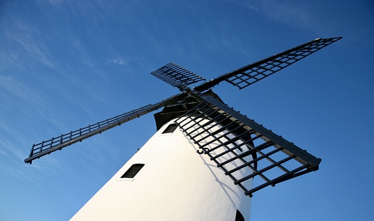 The windmill's huge sails, so prominent, against a deep blue, cloudless sky