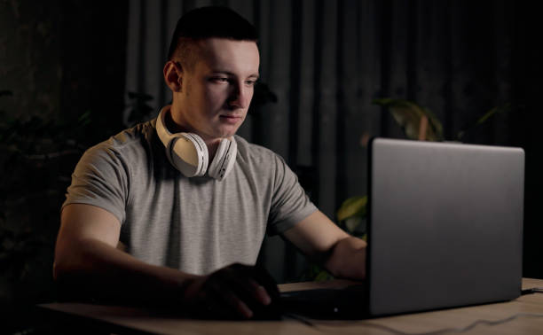 istock Young man freelancer using laptop, typing, scrolling, surfing web, looking at screen at night at home. Male smiling and communication on social media, video conference call. Distance learning online 1791121357