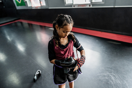 Child girl putting a boxing gloves at gym