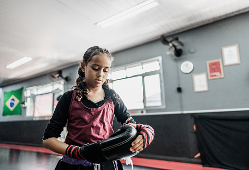 Child girl putting a boxing gloves at gym