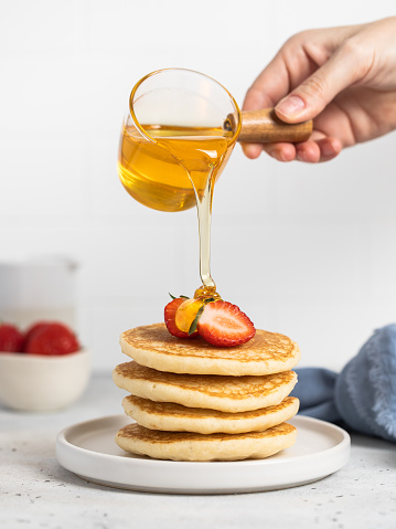 stack of pancakes with strawberries, honey, maple syrup