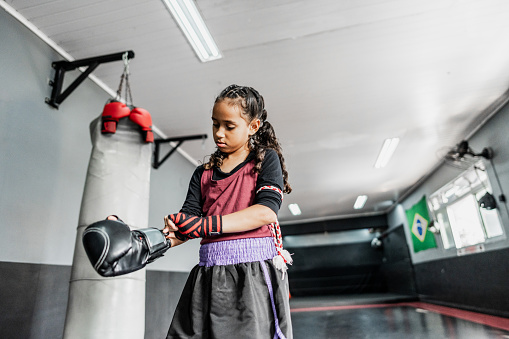 Child girl putting boxing gloves at the gym