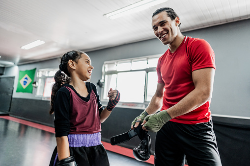 Muay thai instructor talking with child girl at gym