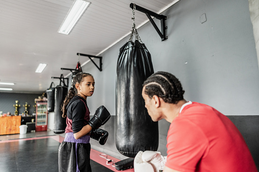 Child girl practicing boxing or muay thai with instructor at gym