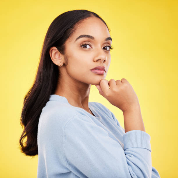 istock Portrait, thinking and a woman on a yellow background in studio feeling thoughtful or contemplative. Face, idea and an attractive young female standing hand on chin while contemplating a thought 1791137529