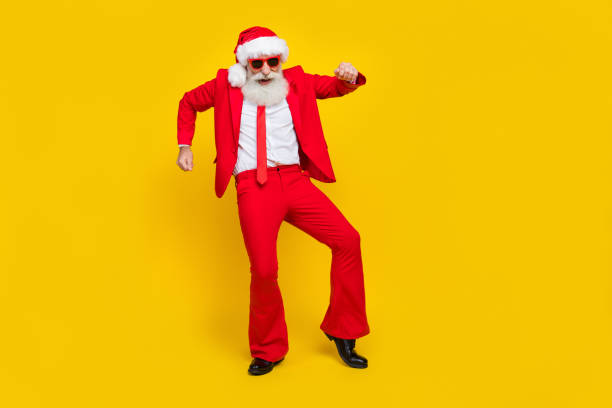 Full length photo of good mood man pensioner dressed red suit santa hat dancing empty space isolated yellow color background stock photo
