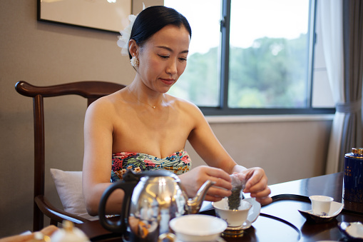 An Asian woman brewing tea