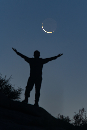 A hiker is standing under the moon