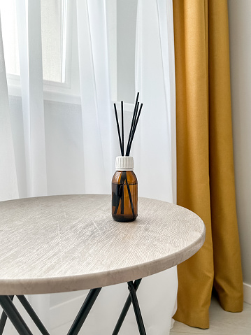 Aroma diffuser on the table, near a gray wall, space for text. Interior decor, aromatic air freshener, incense