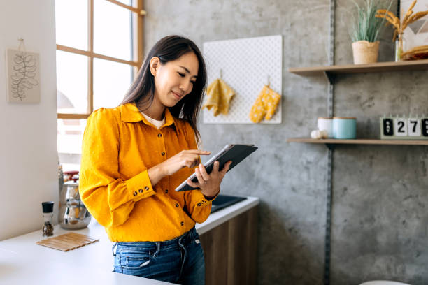 Smiling woman using digital tablet in a domestic kitchen