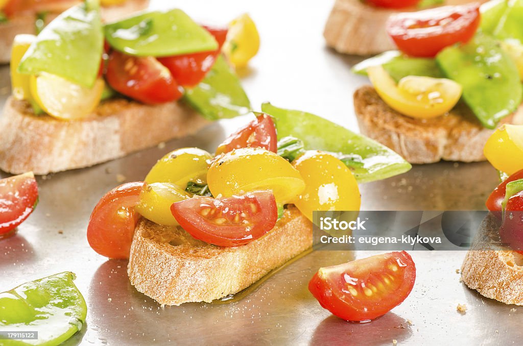 Tomate cereja e neve ervilhas crostini no tabuleiro de cozinhados - Royalty-free Azeite Foto de stock