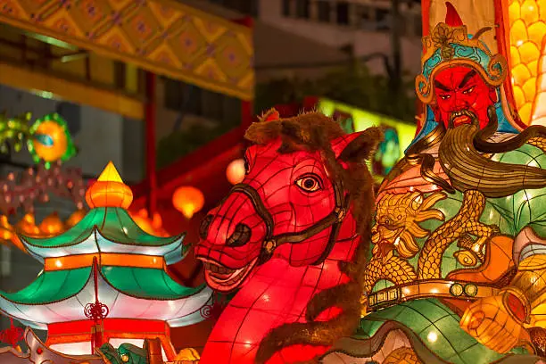 "Multicolored Asian lamps glowing, focus on foreground horseman and stead shaped lantern."