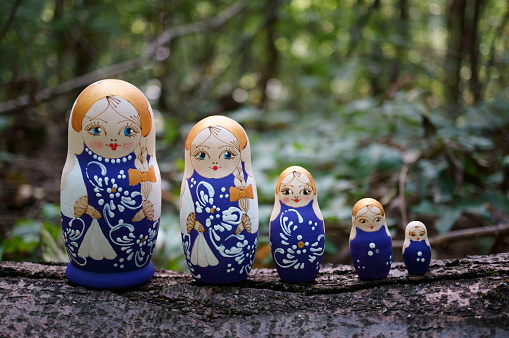 Figurines of beautiful dolls in the forest. Matryoshka dolls.