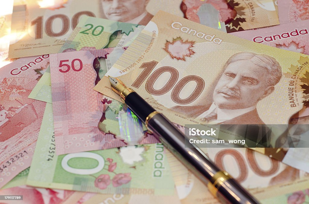 Caneta-tinteiro em uma pilha de dinheiro - Foto de stock de Nota de cem dólares canadenses royalty-free