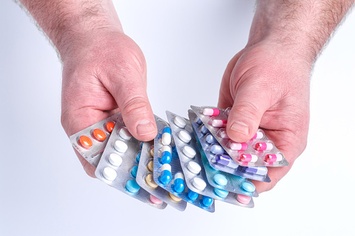 Close-up of hand holding medication blister packs of tablets and capsules against .Colorful pills and medicines in the hand.Medicine and healthcare concept