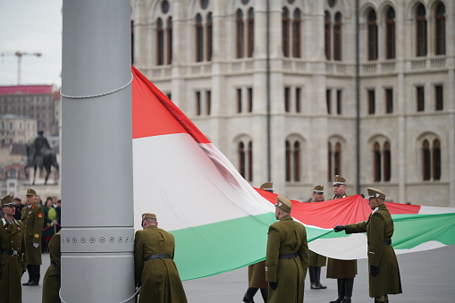 Budapest, Hungary March 15, 2023: Ceremonial raising of the Hungary flag near parliament building in Hungary national day.