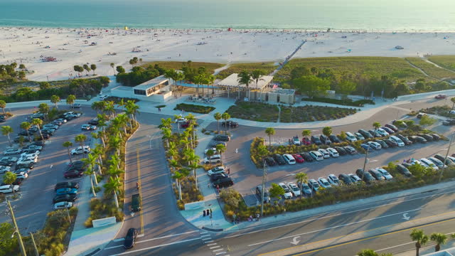 View from above of beachfront car parking area for tourist vehicles at Siesta Key beach with white sands in Sarasota, USA. Popular vacation spot in warm Florida