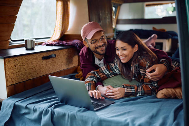 istock Happy couple using laptop while relaxing inside of a camper van in nature. 1791193693