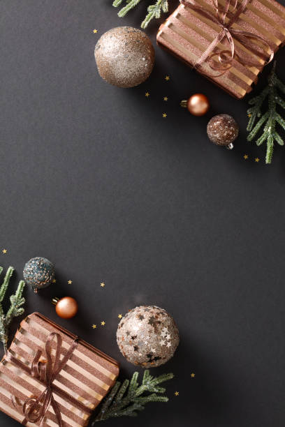 istock Elegant holiday composition with chic bronze gift boxes and baubles on black background. Festive Christmas concept. Luxury design for greeting cards, invitations, or posters 1791197902