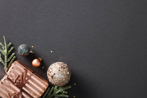 istock Christmas composition on black background featuring festive elements like stylish gift box, copper baubles, confetti, and fir branches. Create your luxury season's greetings with this elegant design 1791202079