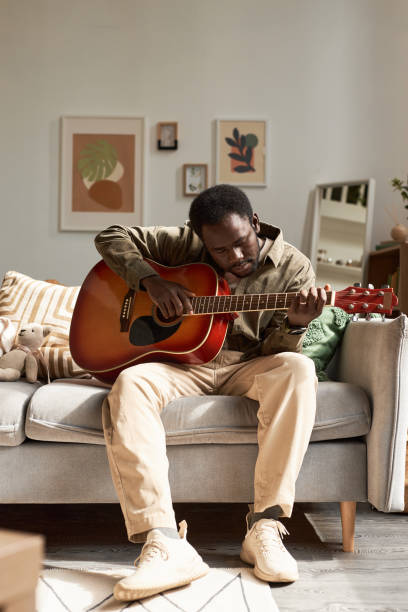 istock Black man playing guitar at home lit by sunlight 1791202709