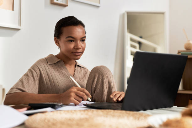 istock Minimal Black young woman using laptop working or studying at home 1791202768