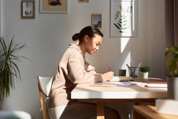 young african american woman writing in notebook at home with sun rays - dagbok bildbanksfoton och bilder